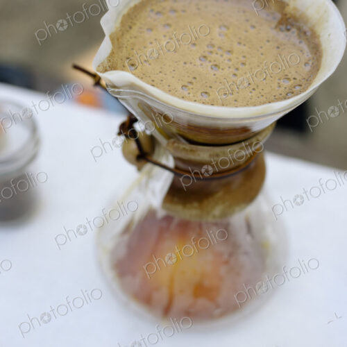 High angle view of a glass coffee maker and filter paper with coffee and water…