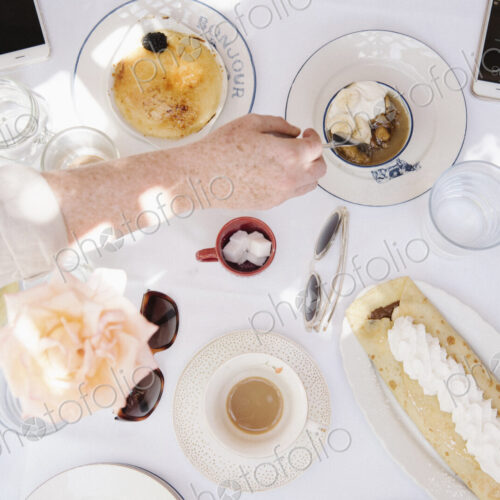 High angle view of a table with food and drink, deserts, pancake with cream, and cups…