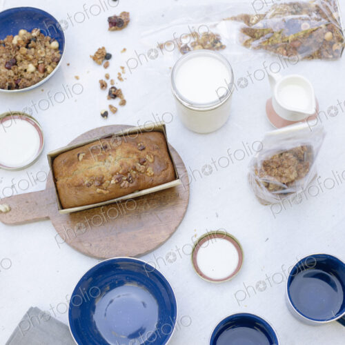 High angle view of a table with mugs and bowls, a cake and cereal.