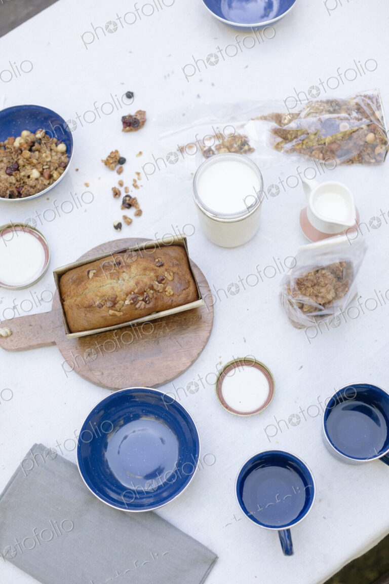 High angle view of a table with mugs and bowls, a cake and cereal.