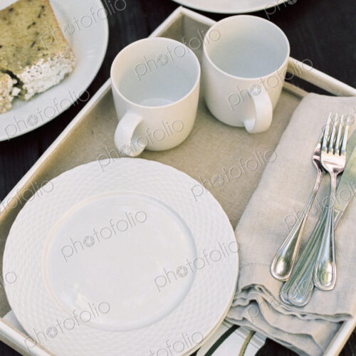 High angle view of a tray with mugs, plates and cutlery, pastries. High angle view of a tray with mugs, plates and cutlery, pastries.
