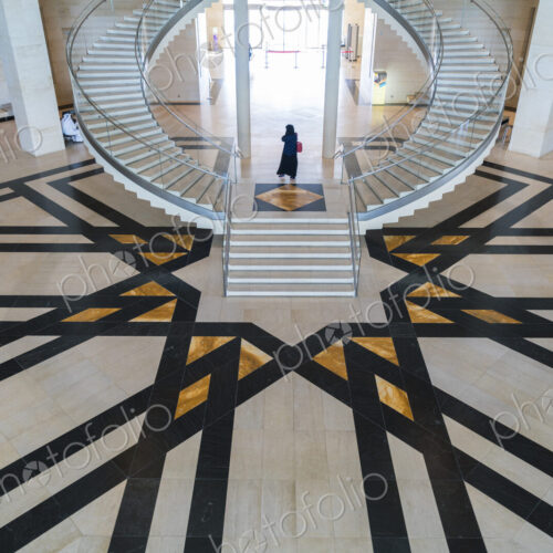 High angle view of building interior with curved freestanding staircase and geometric… High angle view of building interior with curved freestanding staircase and geometric…