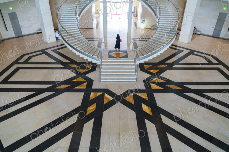 High angle view of building interior with curved freestanding staircase and geometric…
