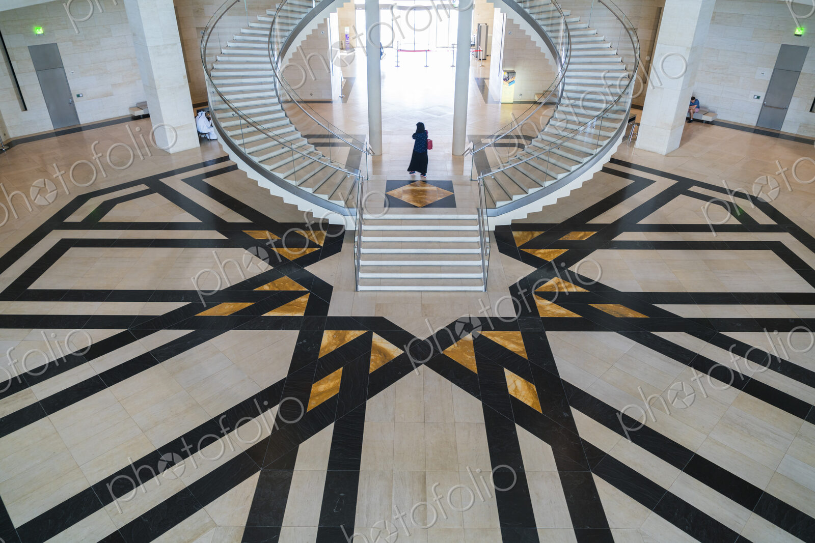 High angle view of building interior with curved freestanding staircase and geometric…