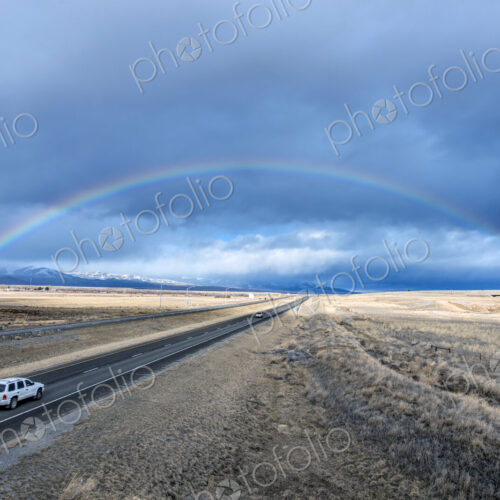 High angle view of car driving to rainbow on remote road High angle view of car driving to rainbow on remote road