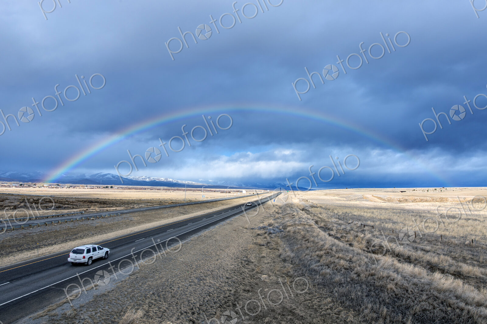 High angle view of car driving to rainbow on remote road
