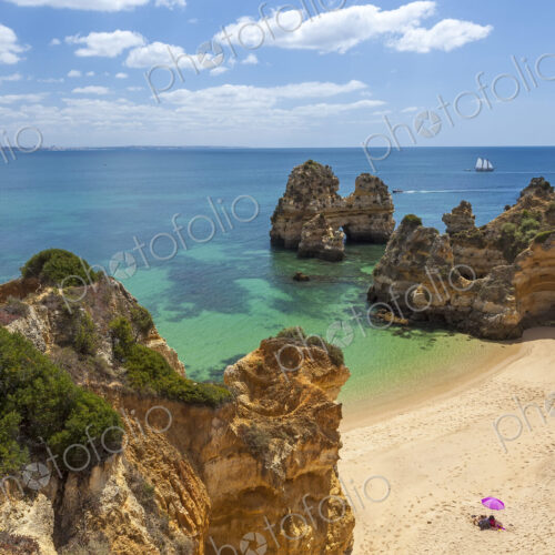 High angle view of coastline with sandy beach and rock formations.