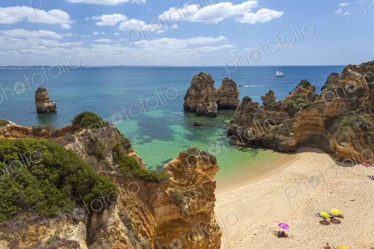 High angle view of coastline with sandy beach and rock formations.