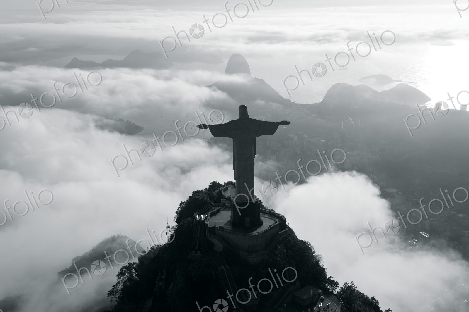 High angle view of colossal Christ Redeemer statue surrounded by clouds, Corcovado,…