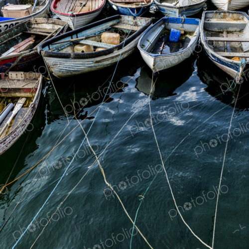 High angle view of colourful wooden fishing boats moored side by side in an harbour. High angle view of colourful wooden fishing boats moored side by side in an harbour.