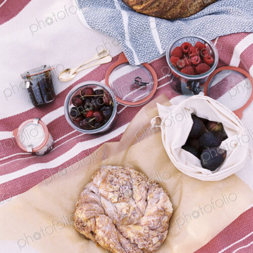 High angle view of food on a picnic blanket, breads and fruits. High angle view of food on a picnic blanket, breads and fruits.