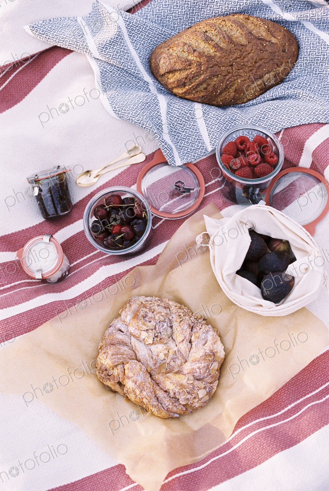 High angle view of food on a picnic blanket, breads and fruits.