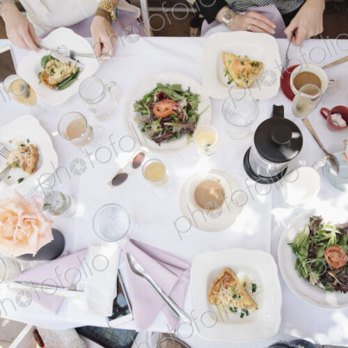 High angle view of four women sitting round a table with food and drink, plates with…