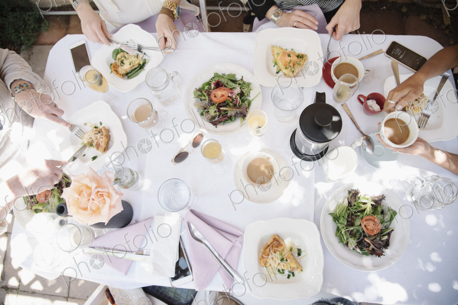 High angle view of four women sitting round a table with food and drink, plates with…