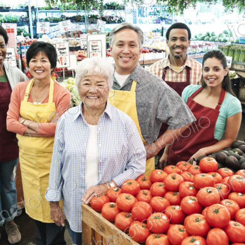 High angle view of group of men and women wearing aprons standing at stall with fresh…