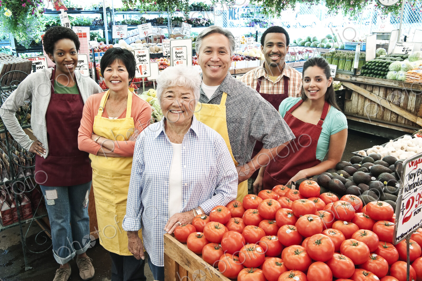 High angle view of group of men and women wearing aprons standing at stall with fresh…