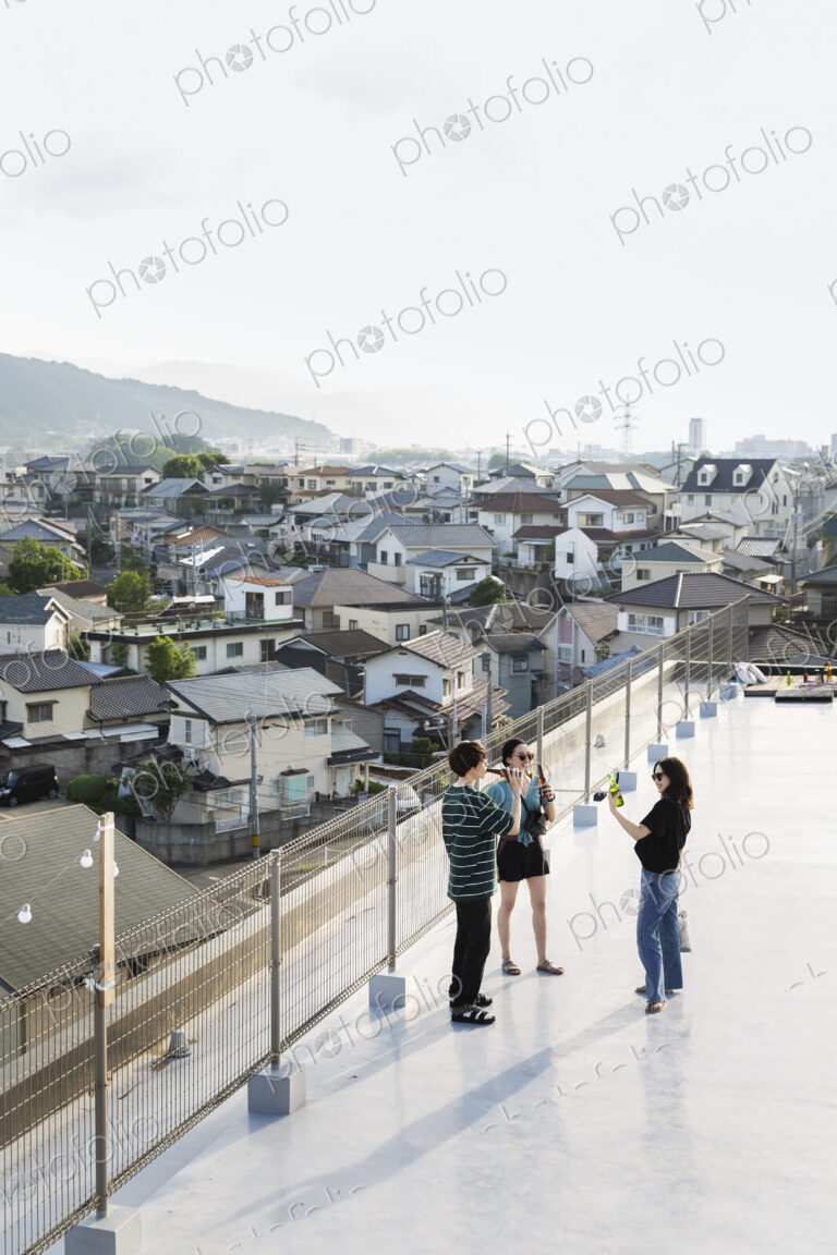 High angle view of group of young Japanese men and women standing on a rooftop in an…