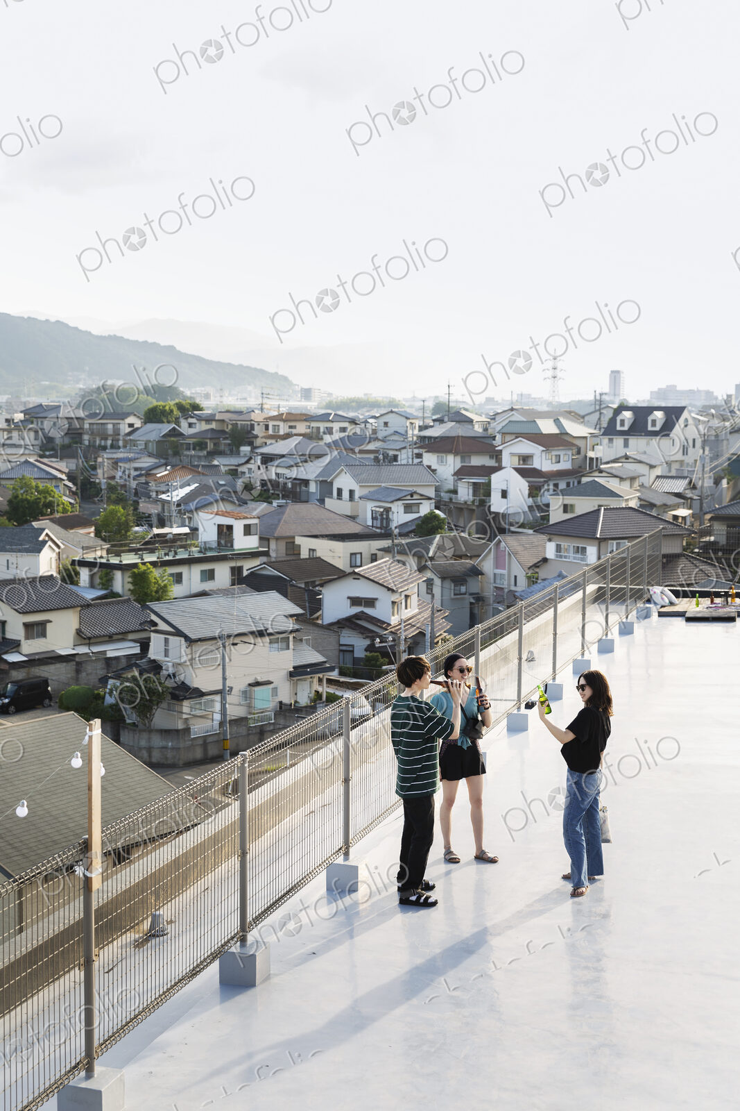 High angle view of group of young Japanese men and women standing on a rooftop in an…