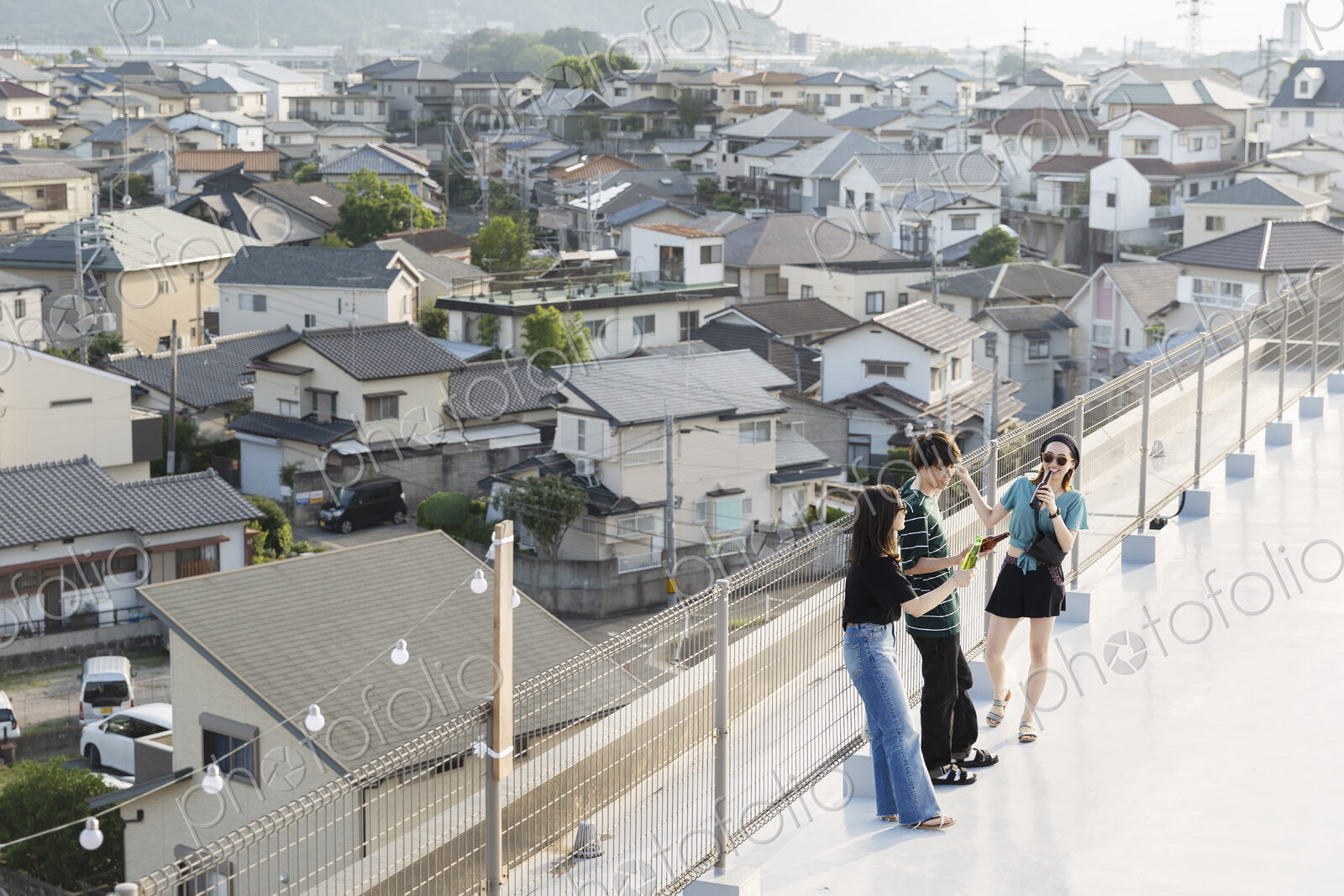 High angle view of group of young Japanese men and women standing on a rooftop in an…