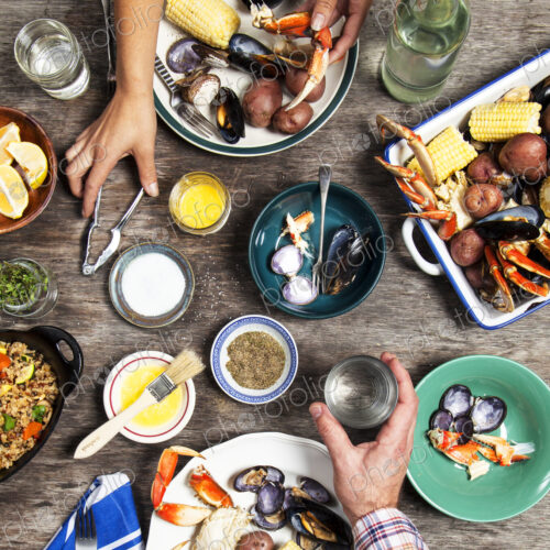 High angle view of hands at seafood dinner High angle view of hands at seafood dinner
