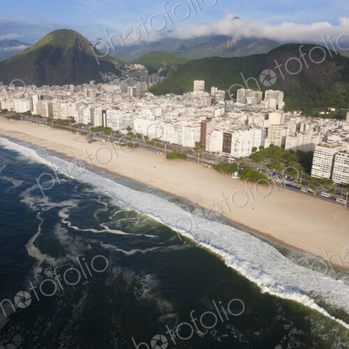 High angle view of long sandy beach lined by tall buildings, mountains in the distance. High angle view of long sandy beach lined by tall buildings, mountains in the distance.
