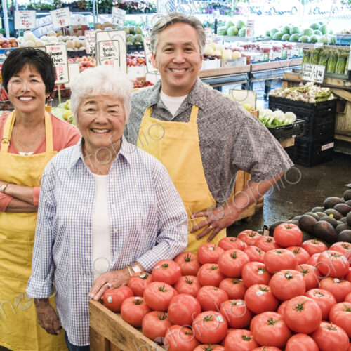 High angle view of man and two women wearing aprons standing at stall with fresh…