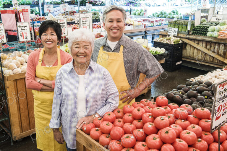 High angle view of man and two women wearing aprons standing at stall with fresh…