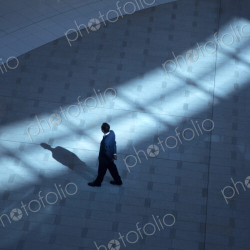 High angle view of man standing in foyer of building, casting shadow.