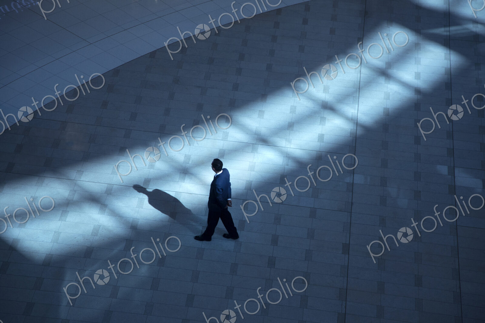 High angle view of man standing in foyer of building, casting shadow.