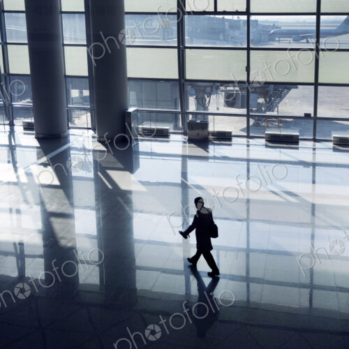 High angle view of man walking along glass wall in airport terminal .