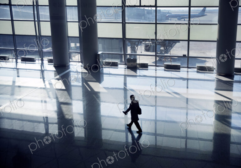 High angle view of man walking along glass wall in airport terminal .