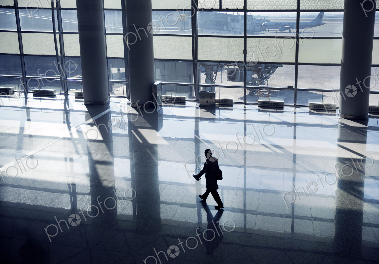 High angle view of man walking along glass wall in airport terminal .