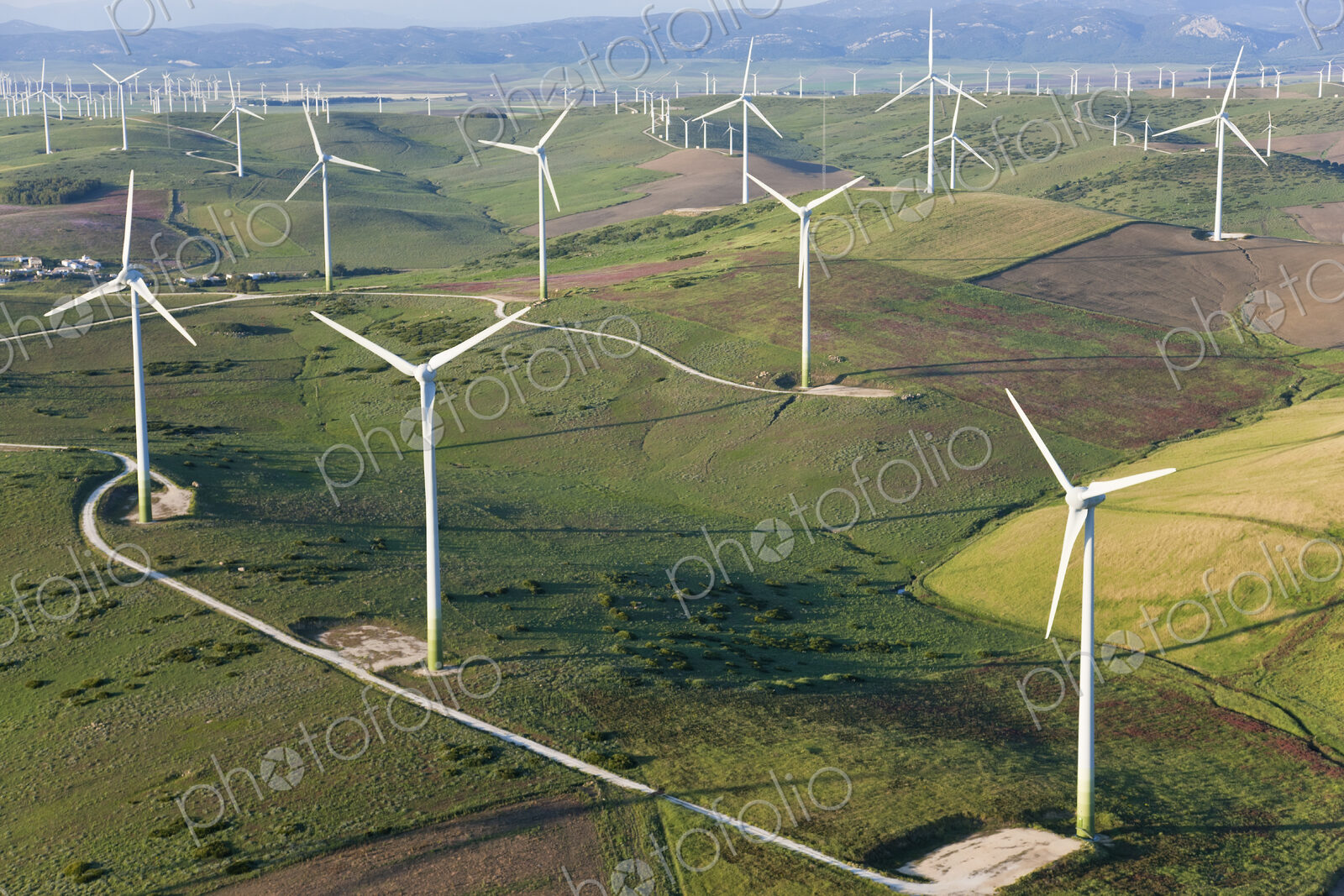 High angle view of rolling landscape with fields and wind turbines.