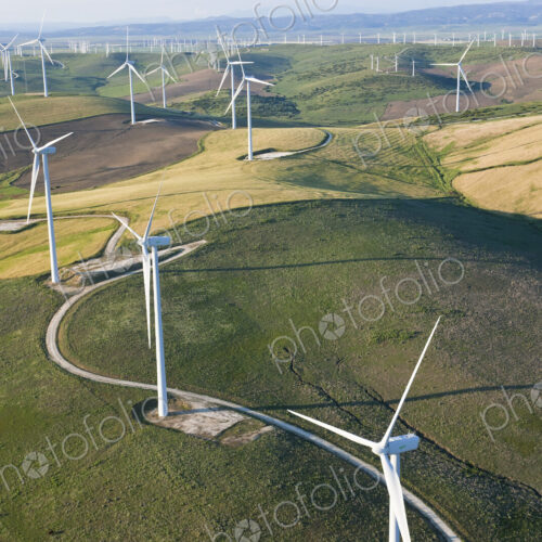 High angle view of rolling landscape with fields and wind turbines.