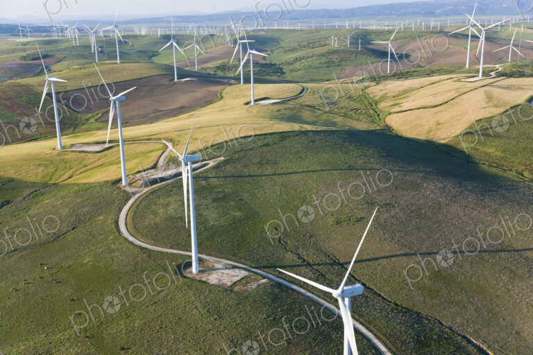High angle view of rolling landscape with fields and wind turbines.