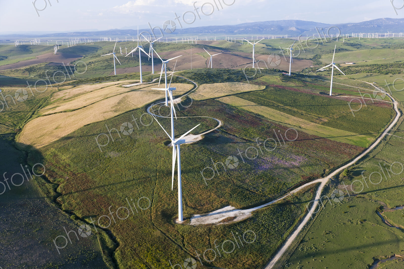 High angle view of rolling landscape with fields and wind turbines.