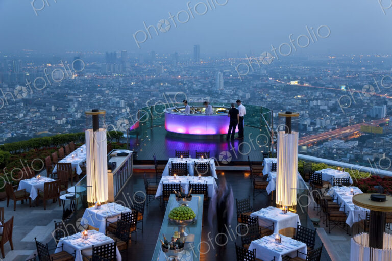 High angle view of rooftop restaurant on a skyscraper, illuminated cityscape in the…