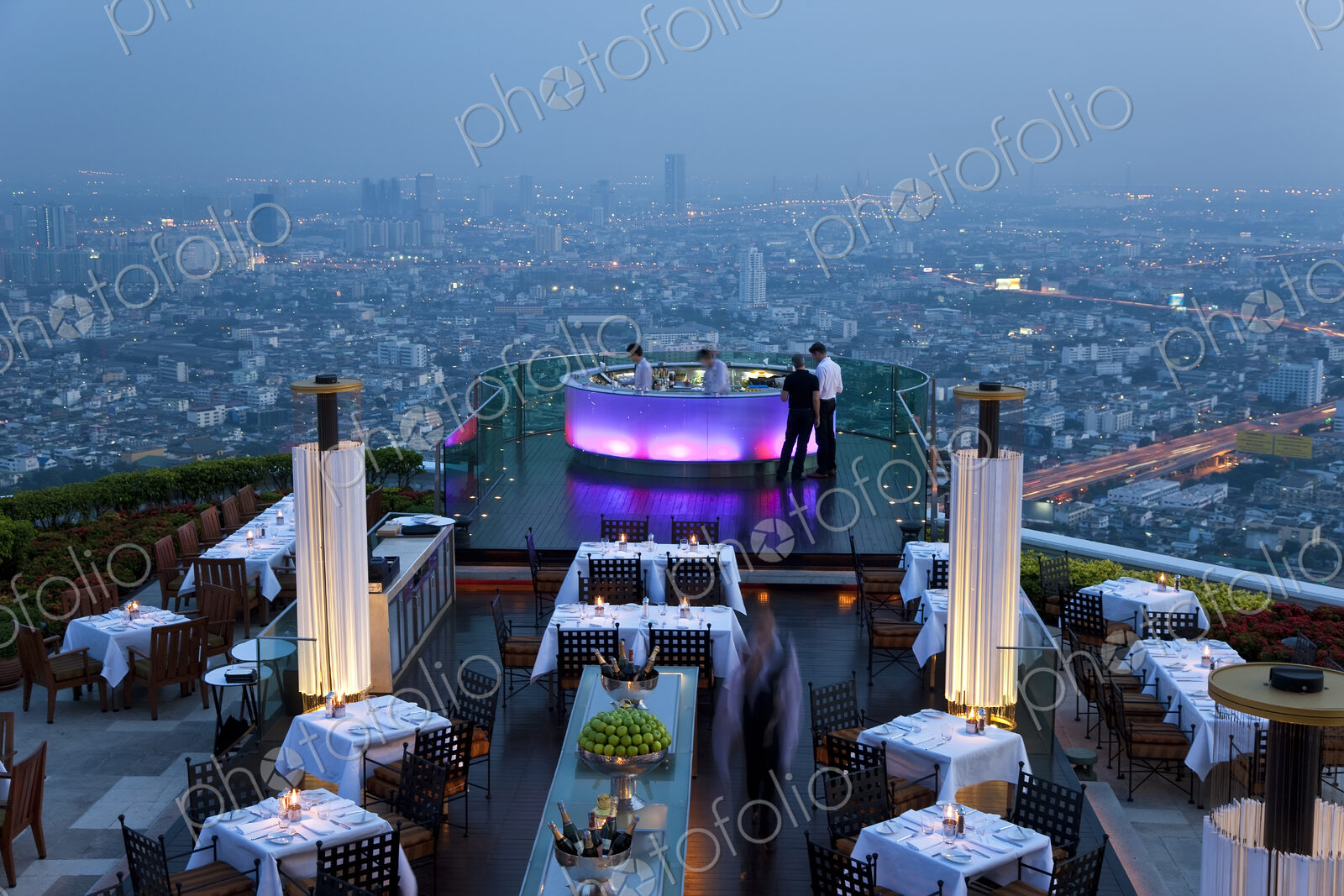 High angle view of rooftop restaurant on a skyscraper, illuminated cityscape in the…