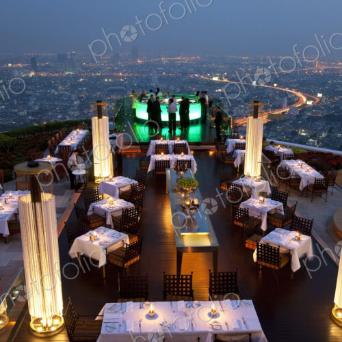 High angle view of rooftop restaurant on a skyscraper, illuminated cityscape in the… High angle view of rooftop restaurant on a skyscraper, illuminated cityscape in the…