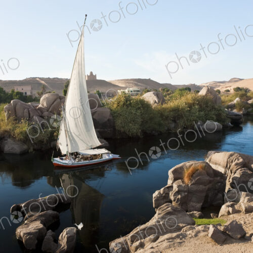 High angle view of sailboat on a river, rocks and sand hills in the distance. High angle view of sailboat on a river, rocks and sand hills in the distance.