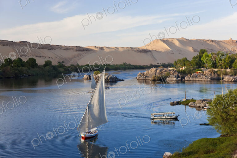 High angle view of sailboats on a river, sand hills in the distance.