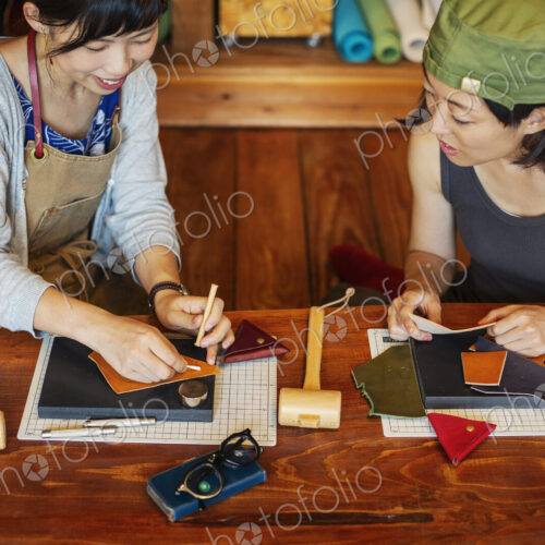 High angle view of two Japanese women sitting at a table, working in a leather shop.
