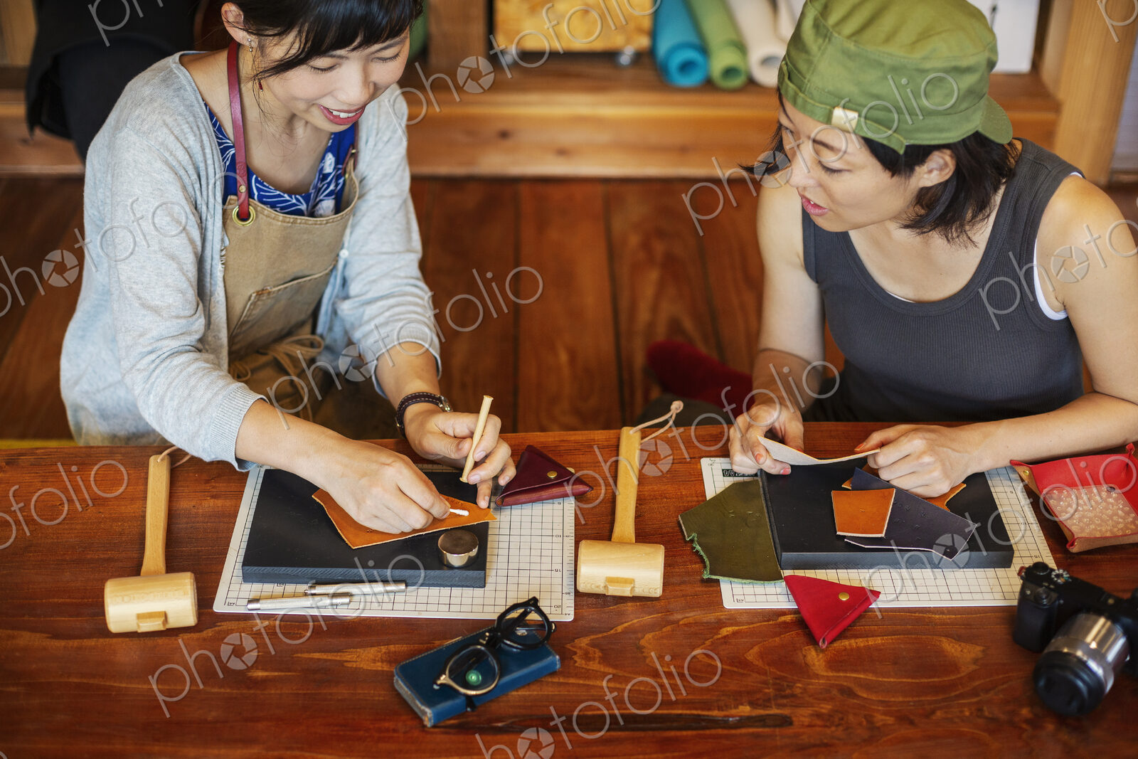 High angle view of two Japanese women sitting at a table, working in a leather shop.