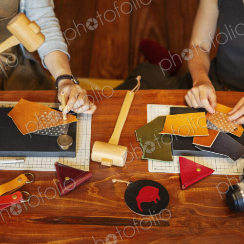 High angle view of two women sitting at a table, working in a leather shop.
