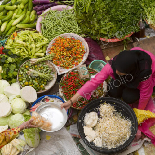 High angle view of vendor selling a selection of fresh vegetables on a street market. High angle view of vendor selling a selection of fresh vegetables on a street market.