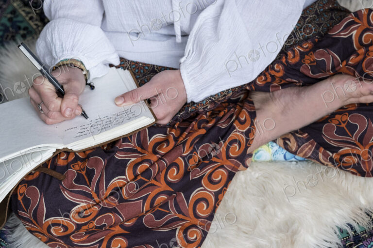 High angle view of woman wearing trousers with floral pattern sitting on shag carpet,…