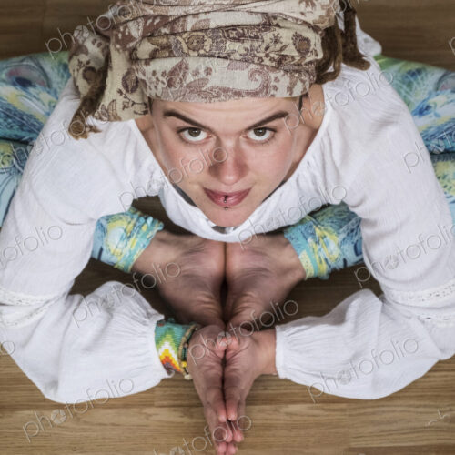 High angle view of woman wearing white blouse and headscarf sitting on floor in yoga…