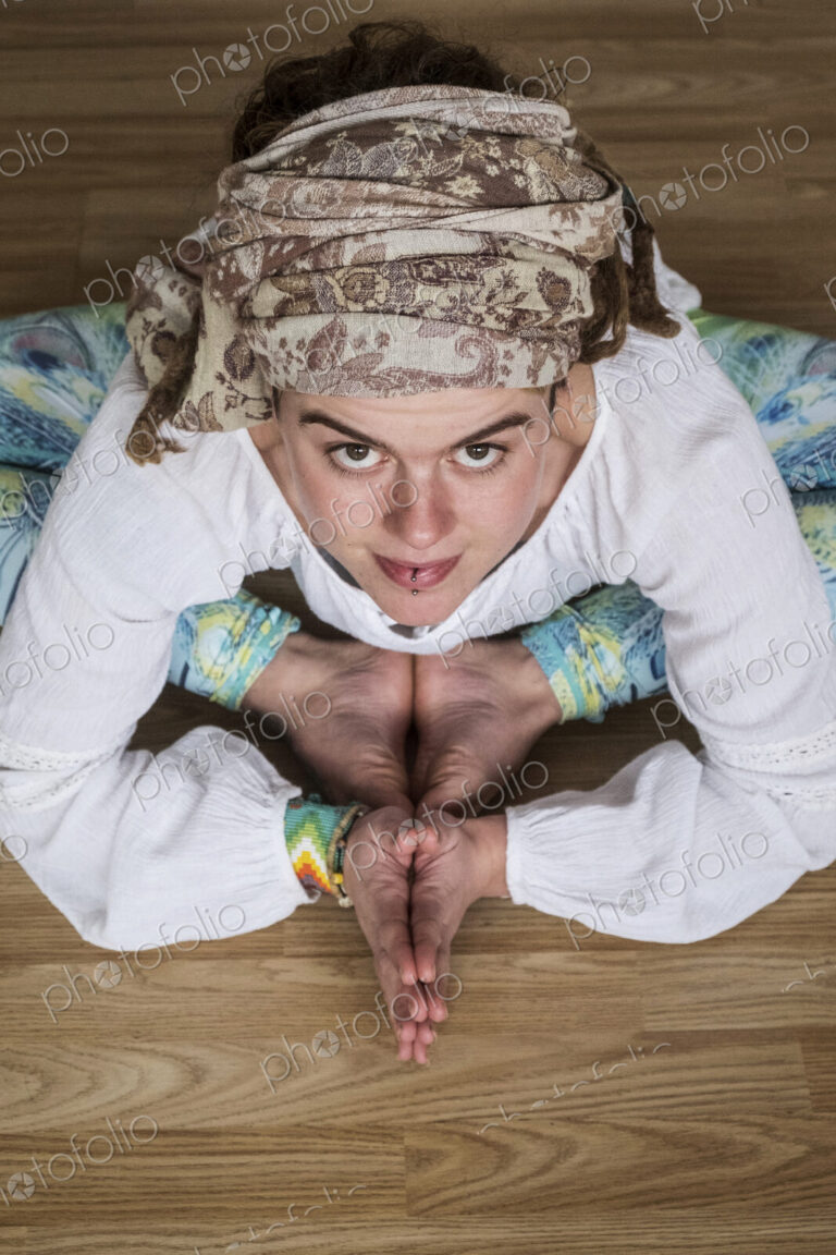 High angle view of woman wearing white blouse and headscarf sitting on floor in yoga…
