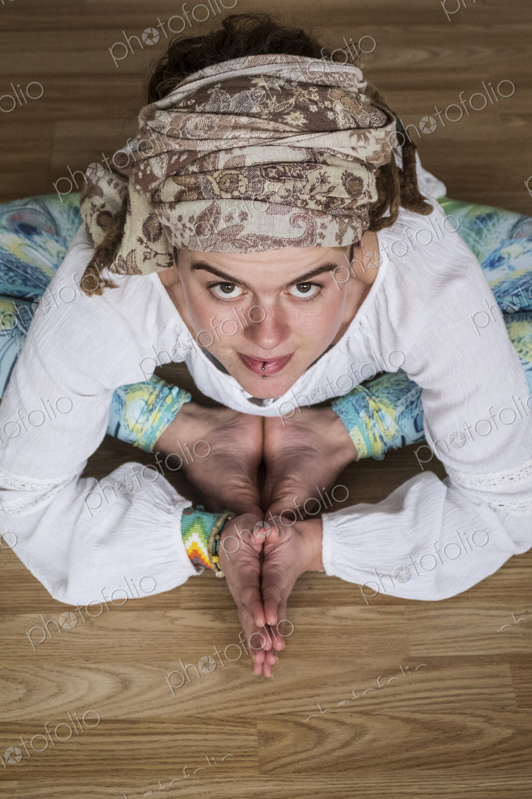 High angle view of woman wearing white blouse and headscarf sitting on floor in yoga…