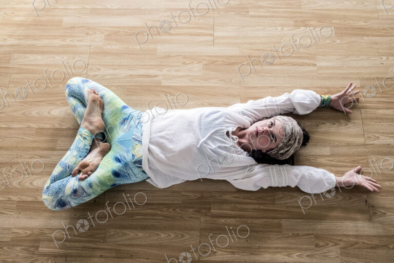 High angle view of young woman wearing headscarf and white blouse lying on her back on…